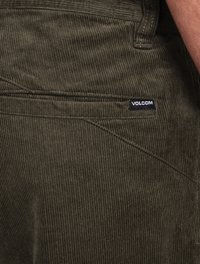 Tkanina w kolorze oliwkowym w kordowym splocie z pionowymi żeberkami, z metką z logo Volcom na tylnej kieszeni oraz kontrastującymi detalami w stichu.