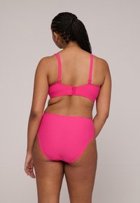 Ljusrosa bikiniset med en strukturerad bralette med justerbara remmar och en hög midja. Slät textur och sömlös design.