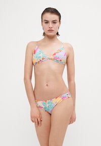 Kolorowy zestaw bikini z trójkątnym topem i niskimi majtkami, oba ozdobione tropikalnym wzorem liści w żywych kolorach.