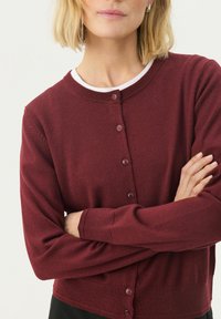 Bordeauxfarbener Cardigan aus Strickstoff mit Rundhalsausschnitt, langen Ärmeln und Knopfverschluss vorne. Glatte Textur.