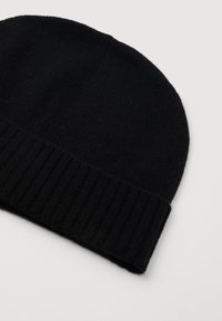 Gorro de punto negro con puño acanalado doblado sobre un fondo claro.