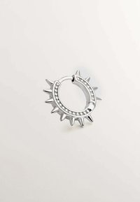 Pendiente de aro plateado con puntas afiladas y una fila de piedras claras a lo largo del borde curvado. Acabado metálico brillante y forma circular.