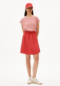 Red striped short-sleeve top paired with a solid red elastic-waist skirt. Worn with white lace-up shoes and a matching red cap.