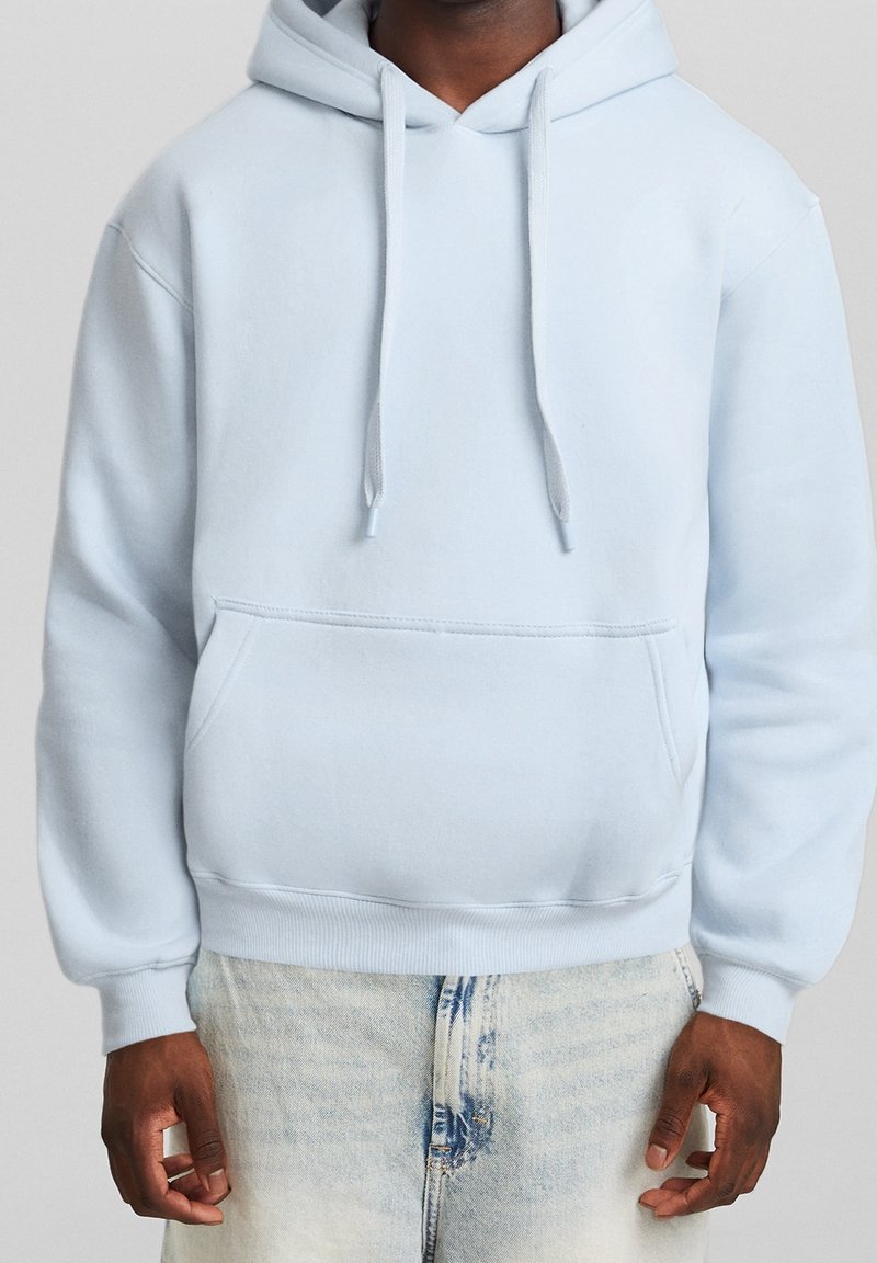 Sudadera de algodón azul claro con un bolsillo frontal tipo canguro, cordones y puños y bajo de canalé. Textura suave, diseño casual.