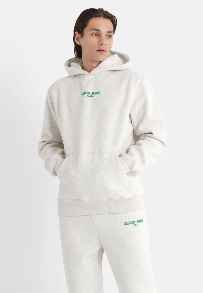 Sudadera gris con capucha y pantalones de chándal a juego, fabricados en un tejido suave, que presentan un texto de logo verde "SIXTH JUNE PARIS" en la parte delantera y en el muslo.