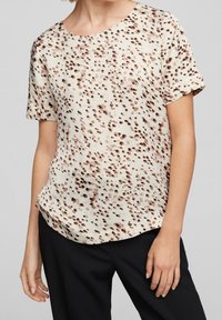 Top a maniche corte color crema con motivo maculato marrone, realizzato in tessuto strutturato, con scollatura rotonda e vestibilità comoda.
