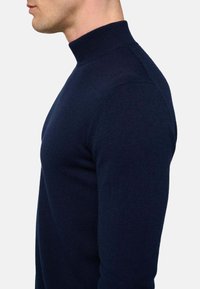 Navyblauer Pullover mit Stehkragen aus weichem Strickstoff. Bietet ein tailliertes Design mit langen Ärmeln und glatter Textur.
