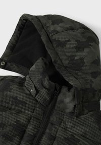 Veste à motifs noirs et verts avec une capuche, dotée d'une doublure intérieure douce, d'une fermeture éclair et de détails à boutons-pression près du cou.