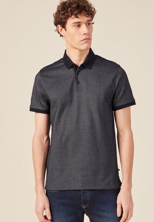 Polo de color gris oscuro hecho de tela texturizada, con un cuello y puños negros, tres botones en el cuello y mangas cortas.