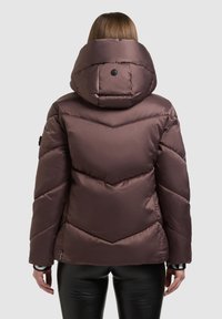 Bruine gewatteerde jas met een hoge kraag, visgraatstiksels en een grote capuchon. Heeft een gladde afwerking en minimalistische hardwaredetails.