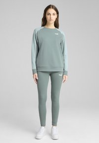 Felpa verde chiaro con maniche lunghe e polsini a coste, abbinata a leggings coordinati. Entrambi presentano accenti del logo in bianco.