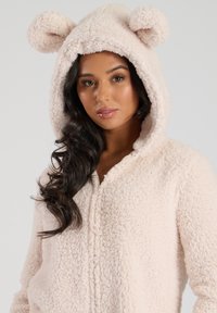 Fluffy roze onesie met een capuchon met berenoren, een rits aan de voorkant en een gestructureerde fleece stof voor warmte en comfort.