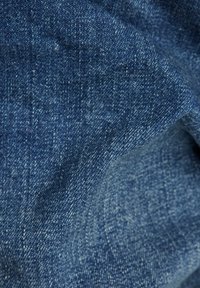 Denim-kangas syvänsinisessä sävyssä, jossa on hienoisia tekstuurivaihteluita, näkyvä kudontamalli ja hienovaraiset haalistumat tietyillä alueilla.