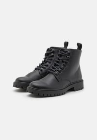 Black leather ankle boots with a round toe, lace-up design, sturdy rubber sole, and pull tab at the back. Textured finish.