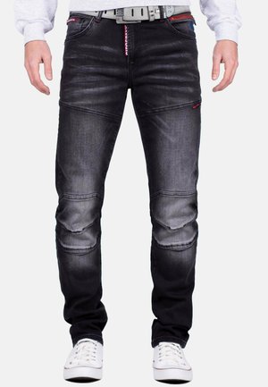 Jeans in denim nero con una finitura sbiadita, caratterizzati da pannelli sulle ginocchia, dettagli rossi e una cintura testurizzata. Progettati con una vestibilità slim e cuciture a contrasto.