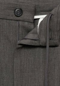 Šedé látkové kalhoty s hladkým povrchem, obsahující černý knoflík, zipové zapínání a vnitřní bílé podšívkové detaily.