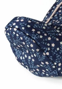 Sac en tissu bleu marine avec un motif floral comprenant des fleurs roses et bleu clair, texture douce, forme arrondie et bordures contrastées le long des bords.
