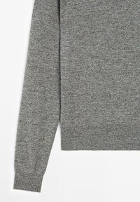 Langer grauer gestrickter Pulloverärmel mit geripptem Bündchen und passendem geripptem Saum vor schlichtem weißem Hintergrund.