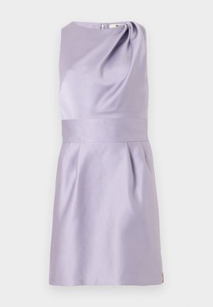 Bezroku lila kleita ar piegulošu vidukli, asimetrisku kakla izgriezumu un mīkstām krokām zem vidukļa uz vienkrāsaina fona.