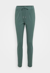 Groene, slim-fit broek met een trekkoord in de taille, gemaakt van zachte stof. Heeft plooien aan de voorkant en taps toelopende pijpen.