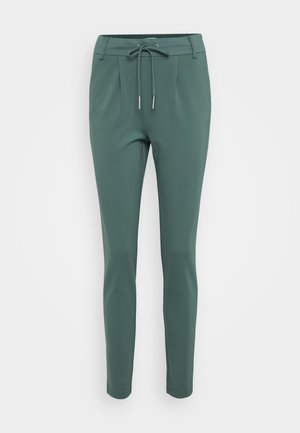 Pantalones verdes de corte ajustado con cintura elástica, fabricados en un tejido suave. Presentan pliegues en la parte delantera y piernas estrechas.