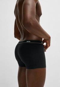 Zwarte boxershorts van rekbare stof, met een merkband in het wit met een gouden accent. Strak aansluitend ontwerp, minimale naden.