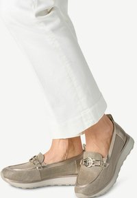 Buty wsuwane w metalicznym beżu z siateczkową cholewką, elastycznymi akcentami i dekoracyjną metalową klamrą. Lekka podeszwa i zaokrąglony nosek.