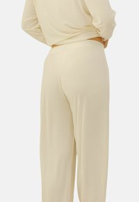 Ensemble de vêtements de détente couleur crème avec une texture côtelée, une taille ajustée et un pantalon ample. Design minimaliste et tissu doux.