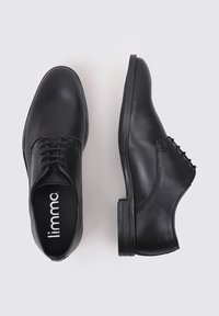 Zapatos de vestir de cuero negro con una textura suave, puntera redonda y diseño de cordones. Presentan un ligero tacón y plantilla con marca.
