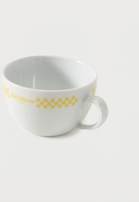 Tasse en céramique blanche avec un motif à damier jaune et une anse, vide, présentée sur un fond blanc.