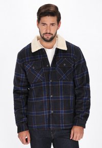 Sort og blåternet jakke med en kremfarvet faux fur krave, knappet front, to brystlommer og lange ærmer. Teksturområde.