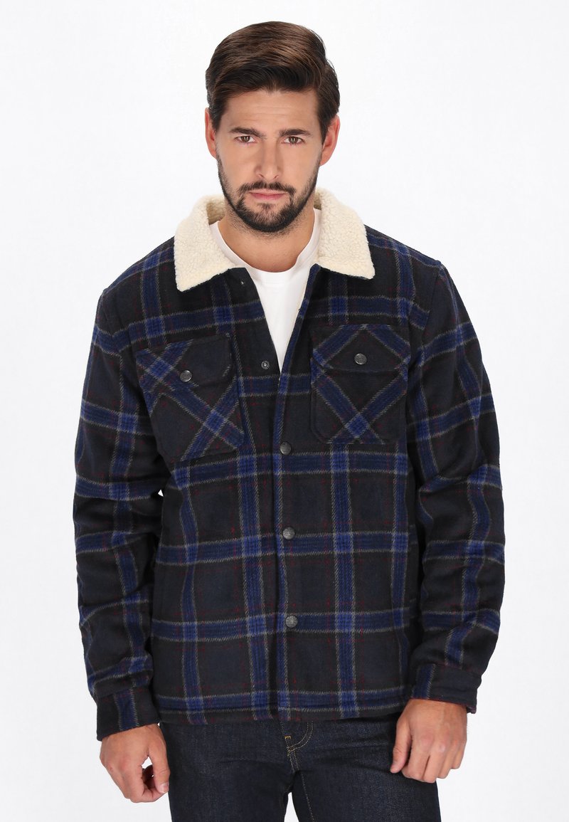 Sort og blåternet jakke med en kremfarvet faux fur krave, knappet front, to brystlommer og lange ærmer. Teksturområde.