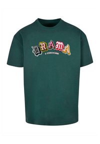 Grønn bomulls T-skjorte med multikolor broderte bokstaver som staver "DRAMA" over "I CHOOSE." Korte ermer og rund hals.