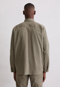 Olivgrünes Langarmhemd mit klassischem Kragen und Knopfmanschetten, gefertigt aus einem glatten Stoff mit lockerem Schnitt und Rückenpasse.