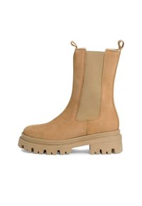 Bottines en suede tan avec panneaux latéraux élastiques, tirettes en boucle, semelle en caoutchouc épaisse et motif de semelle pour une bonne traction.