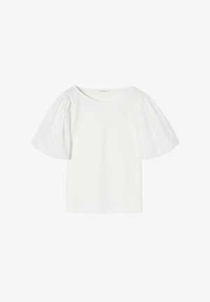 Valge lühikeste varrukatega topp ümmarguse kaelusega. Puffvarrukad, mis on valmistatud tekstuurist ja tikandist. Sile keha materjal, minimalistlik disain.