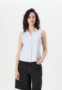 Light blue sleeveless button-down shirt with vertical white stripes, paired with black denim shorts. Smooth texture and collar detail visible.