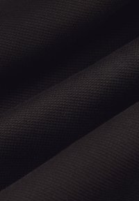 Czarna tkanina o fakturze z tkanego wzoru, charakteryzująca się miękkimi fałdami i matowym wykończeniem, z wieloma złożeniami i warstwami.