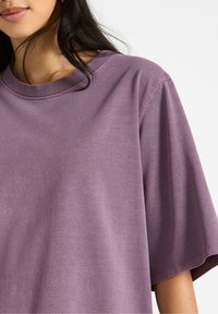 Overdimensioneret t-shirt med korte ærmer i dæmpet lilla. Lavet af blødt bomuldsstof, med en klassisk crew neckline og en glat tekstur.