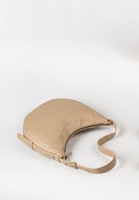 Borsa in pelle beige con forma curva, chiusura con zip superiore e una lunga tracolla regolabile. Texture liscia con design minimalista.