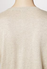 Beige knit sweater with a wide, ribbed neckline and a soft texture. The fabric is lightweight and the overall shape is relaxed.
