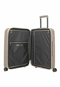 Maleta rígida beige abierta con compartimentos interiores negros, ruedas dobles, asa telescópica y bolsillos con cremallera en ambos lados.