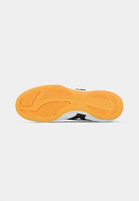 Athletic shoe sole with an orange rubber bottom, featuring textured patterns and a white and black upper for grip and support.