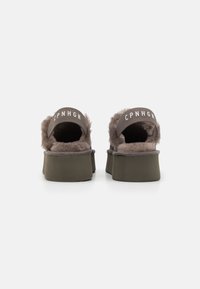 Brune plattform slide sandaler med kunstig pels og elastiske stropper, med teksten "CPNHGN" på baksiden. Rund form og teksturert overdel.