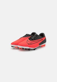 Scarpe da calcio rosse e nere con tomaia testurizzata, suola bianca e tacchetti arancioni. Presentano un design elegante con un logo swoosh prominente.