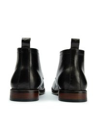 Black leather ankle boots with a smooth texture, rounded toe, and a short block heel featuring a brown wood accent and pull tab.