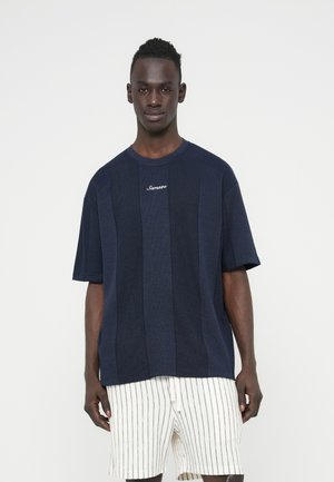 Marineblå kortærmet skjorte med tekstureret paneldesign, rund halsudskæring og lille hvidt logo på brystet, kombineret med stribede shorts.