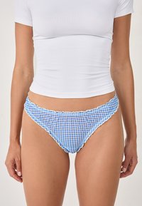 Blaue und weiße Gingham-hüftslip mit Rüschendetails. Hergestellt aus leichtem Stoff, mit einem tief sitzenden Schnitt und weicher Textur.