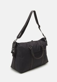 Sac en tissu noir avec doubles poignées et bandoulière réglable, comportant une poche zippée et une texture lisse. Design minimal sans motifs.