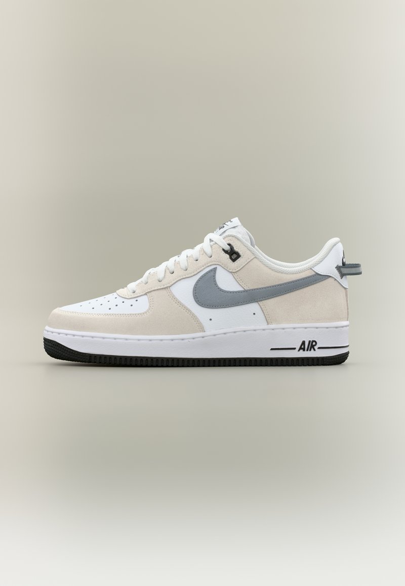 Witte leren en grijze suède sneaker met geperforeerde neus, ronde veters en zwarte rubberen zool. Voorziene van een "AIR" label aan de zijkant.